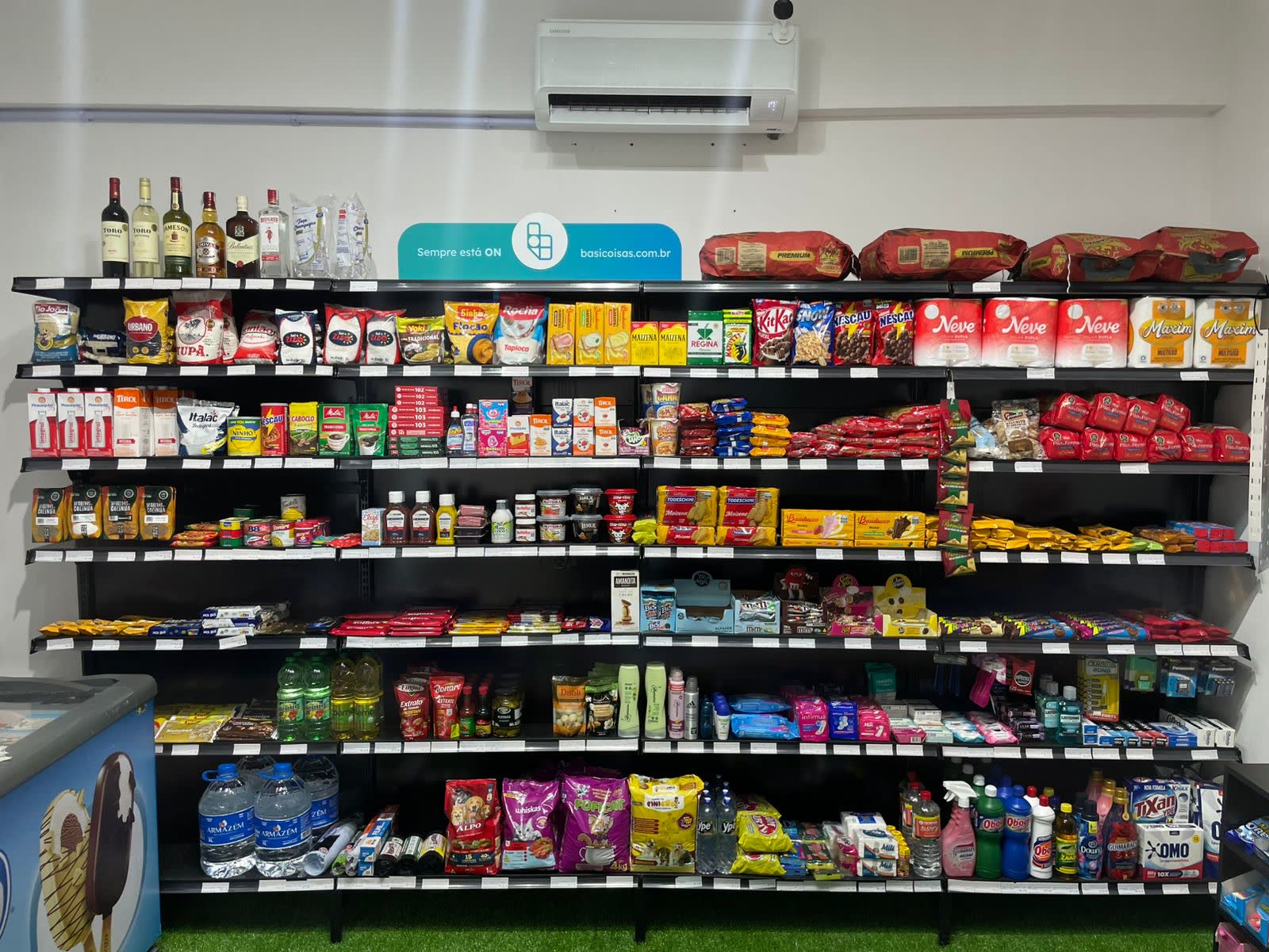 Parede de gôndolas com mercearia, bebidas e limpeza